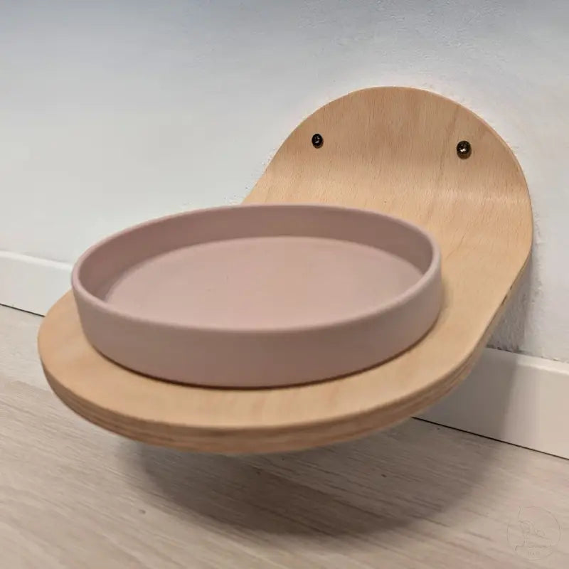 Wandmontierte hölzerne Katzenfutterstation mit rosa Schale.