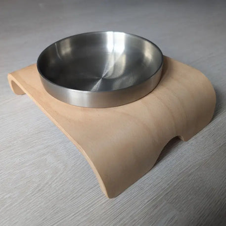 Metallschale auf geschwungenem Holzständer.